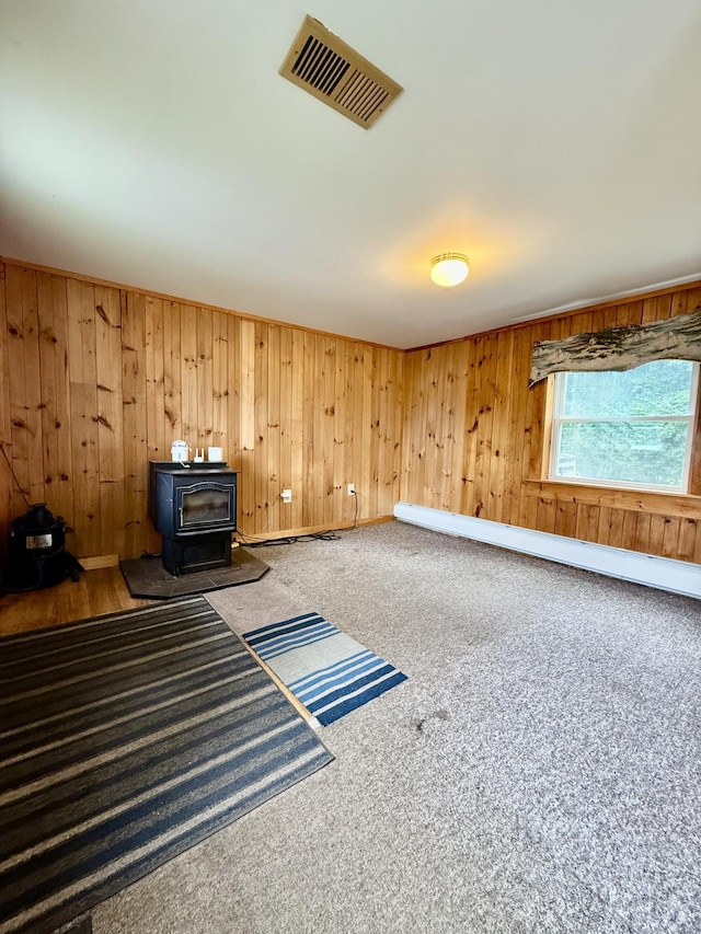 69 Lafayette St, Calais, ME 04619 - unfurnished room featuring a wood stove, a baseboard radiator, carpet, and wood walls