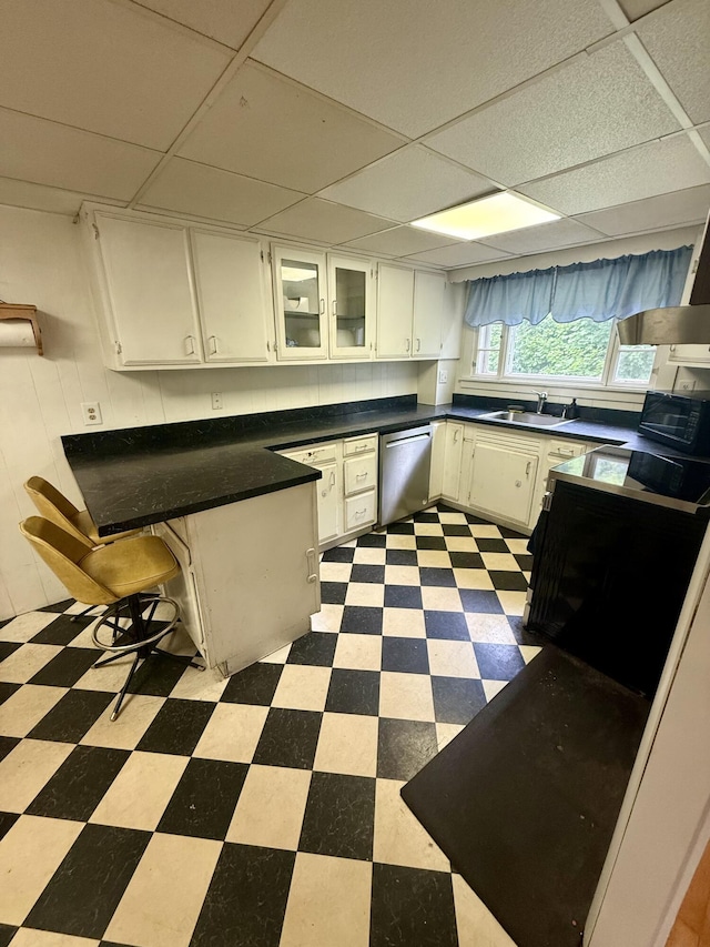 69 Lafayette St, Calais, ME 04619 - kitchen featuring stainless steel dishwasher, tile patterned floors, a drop ceiling, white cabinets, and a peninsula