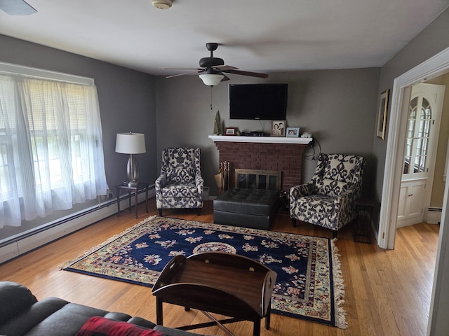 125 Connecticut Ave, Millinocket, ME 04462 - living room with baseboard heating, wood finished floors, a ceiling fan, and a fireplace