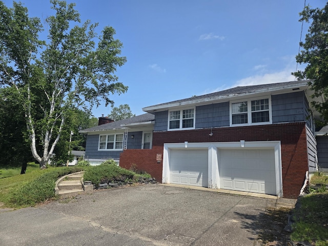 125 Connecticut Ave, Millinocket, ME 04462 - tri-level home featuring asphalt driveway, brick siding, a chimney, and an attached garage