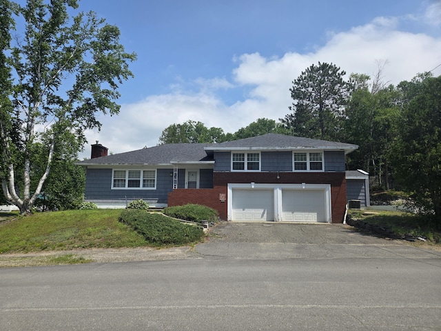 125 Connecticut Ave, Millinocket, ME 04462 - split level home with driveway, an attached garage, a chimney, and brick siding