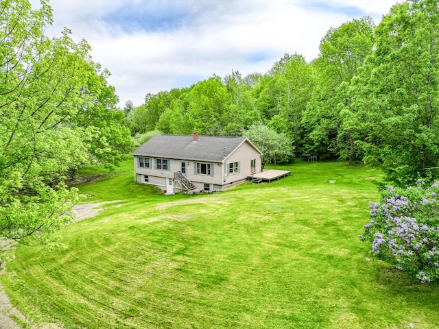 23 Mccutcheon Way, Sidney, ME 04330 - rear view of house with a chimney, a wooden deck, a lawn, and a forest view