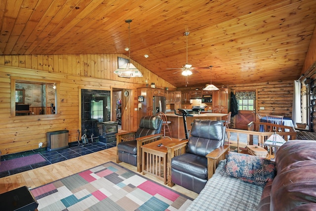 23 Mccutcheon Way, Sidney, ME 04330 - living area with vaulted ceiling, wood finished floors, wooden ceiling, a wood stove, and wood walls