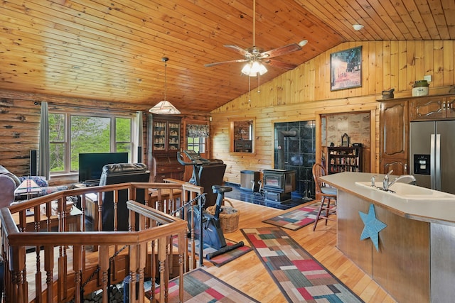 23 Mccutcheon Way, Sidney, ME 04330 - living room with a wood stove, wooden ceiling, light wood finished floors, wooden walls, and ceiling fan