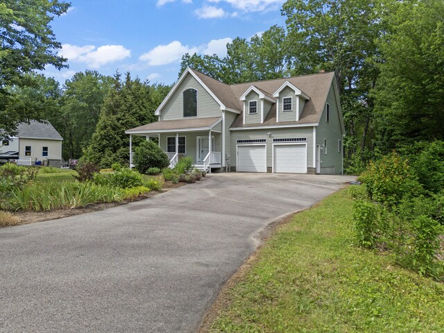 17 Tuttle Ln, Wells, ME 04090 - view of front facade featuring asphalt driveway, a porch, a garage, and roof with shingles