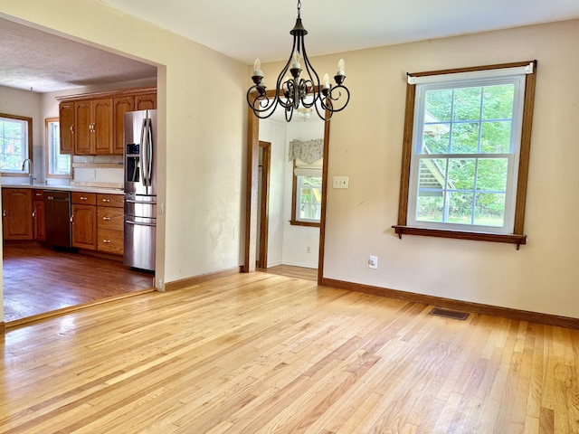 1606 Avenue Rd, Exeter, ME 04435 - kitchen featuring appliances with stainless steel finishes, light wood-style floors, a chandelier, light countertops, and plenty of natural light