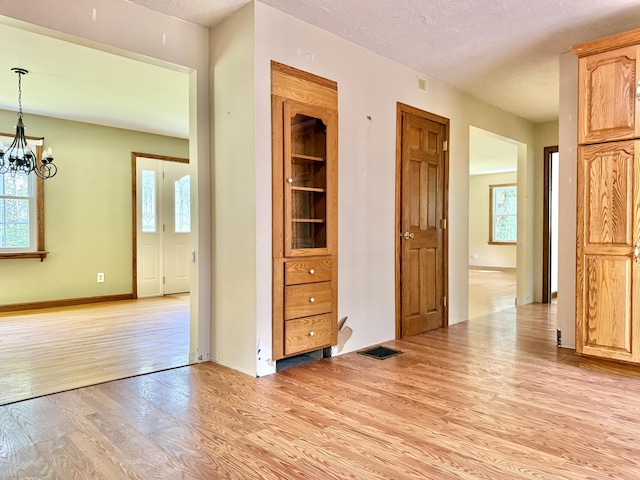 1606 Avenue Rd, Exeter, ME 04435 - unfurnished room featuring light wood-style flooring, plenty of natural light, a chandelier, and a textured ceiling