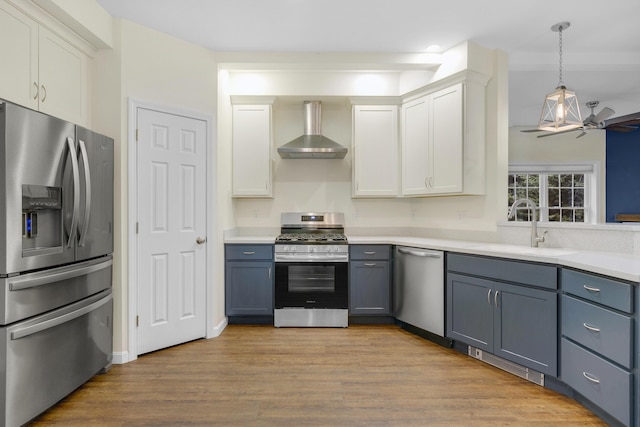 1031 Hallowell Rd, Durham, ME 04222 - kitchen featuring appliances with stainless steel finishes, wall chimney range hood, white cabinetry, and light countertops