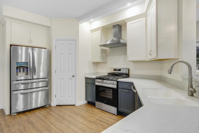 1031 Hallowell Rd, Durham, ME 04222 - kitchen featuring stainless steel appliances, wall chimney range hood, light stone counters, light wood finished floors, and white cabinetry
