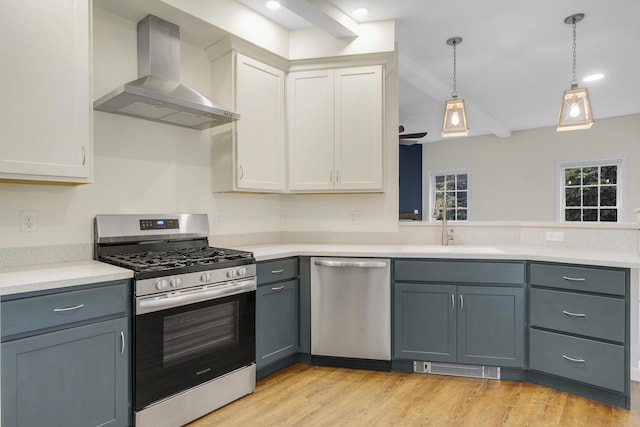 1031 Hallowell Rd, Durham, ME 04222 - kitchen with stainless steel appliances, wall chimney range hood, light countertops, decorative light fixtures, and light wood finished floors