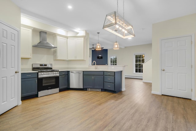 1031 Hallowell Rd, Durham, ME 04222 - kitchen with wall chimney range hood, appliances with stainless steel finishes, a peninsula, light wood-style flooring, and light countertops
