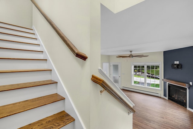 1031 Hallowell Rd, Durham, ME 04222 - staircase with baseboard heating, a glass covered fireplace, wood finished floors, and a ceiling fan