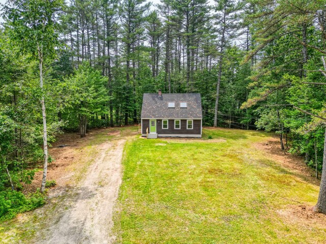 117 Badger Cir, Limerick, ME 04048 - view of front of house with driveway, an outbuilding, a front yard, a chimney, and a view of trees