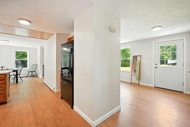 117 Badger Cir, Limerick, ME 04048 - entrance foyer featuring a baseboard radiator, a textured ceiling, light wood finished floors, and healthy amount of natural light