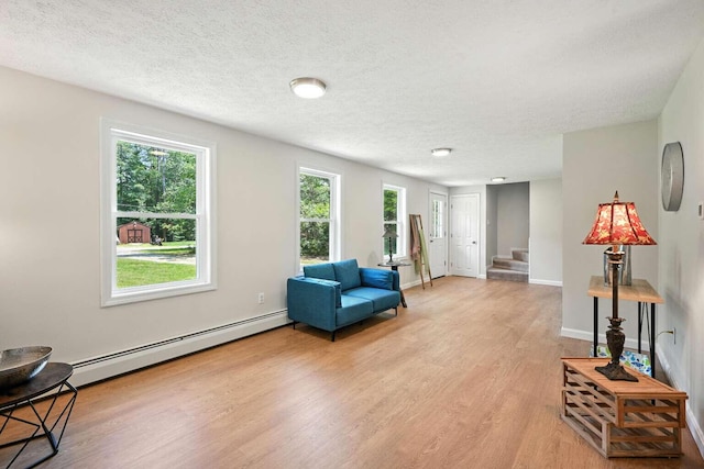 117 Badger Cir, Limerick, ME 04048 - living area featuring a baseboard radiator, light wood-style floors, stairs, healthy amount of natural light, and a textured ceiling