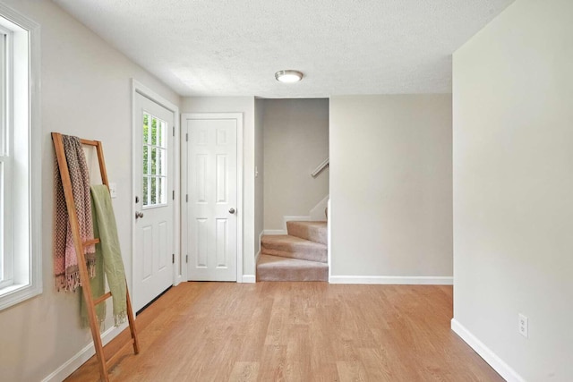 117 Badger Cir, Limerick, ME 04048 - foyer with light wood-style flooring, stairs, and a textured ceiling