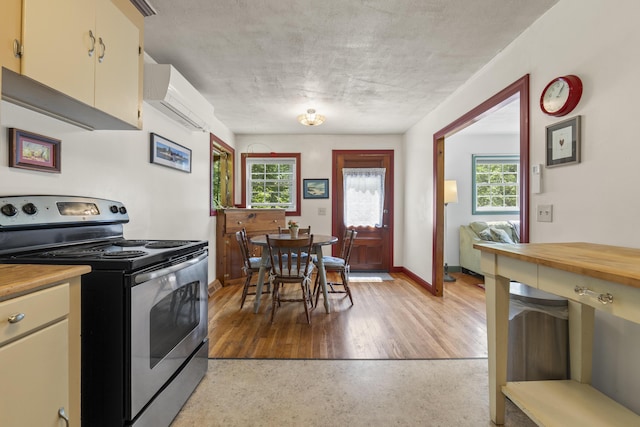 490 Cross Point Rd, Edgecomb, ME 04556 - kitchen featuring stainless steel range with electric stovetop, a wall mounted AC, and butcher block countertops