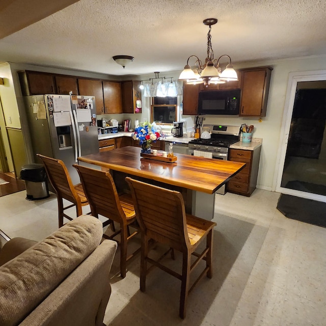 96 N Main St, Milbridge, ME 04658 - kitchen with stainless steel appliances, a textured ceiling, hanging light fixtures, dark brown cabinetry, and wooden counters