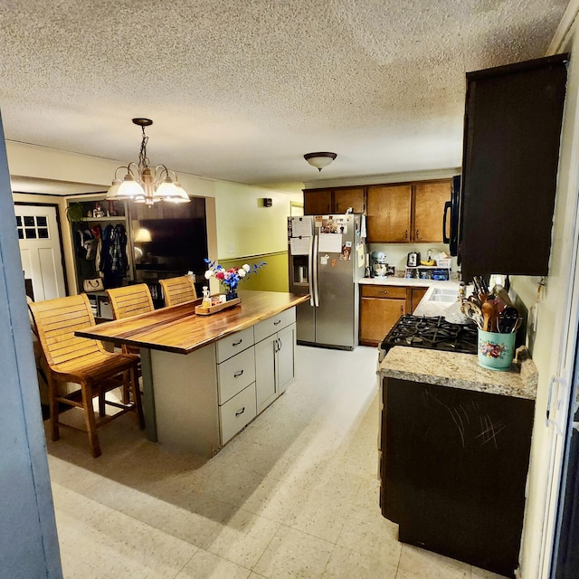 96 N Main St, Milbridge, ME 04658 - kitchen with stainless steel refrigerator with ice dispenser, black microwave, light countertops, a textured ceiling, and brown cabinetry