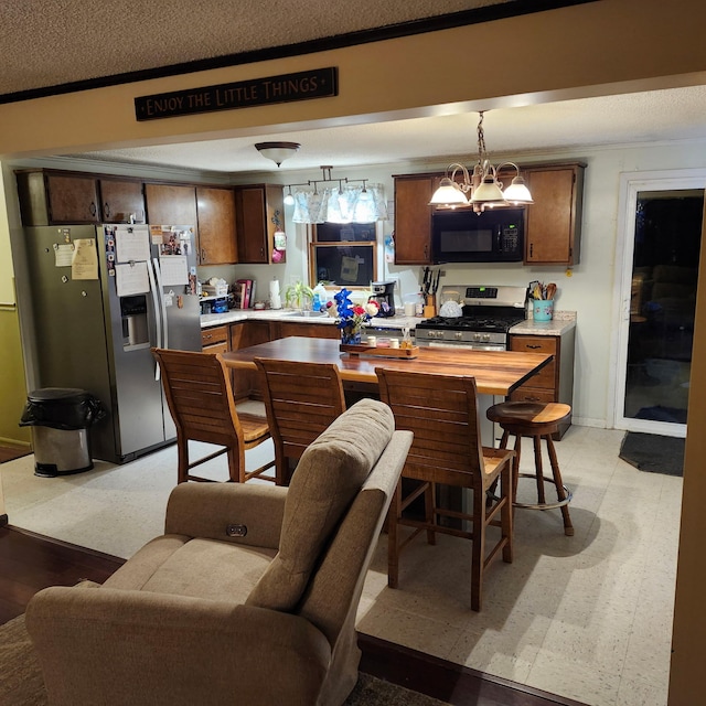 96 N Main St, Milbridge, ME 04658 - kitchen with appliances with stainless steel finishes, light countertops, hanging light fixtures, ornamental molding, and dark brown cabinetry