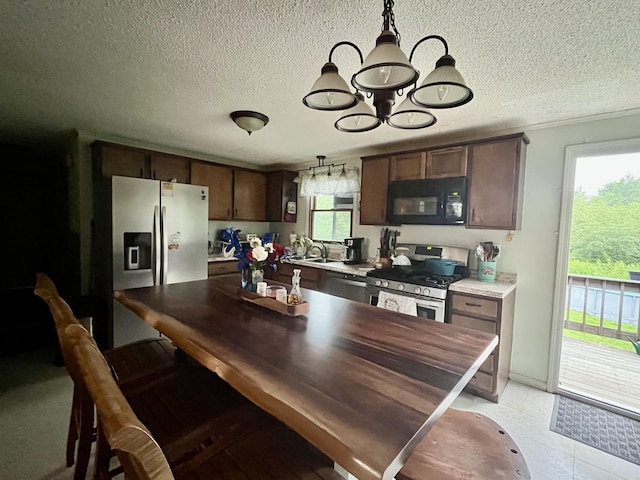 96 N Main St, Milbridge, ME 04658 - kitchen featuring stainless steel appliances, a textured ceiling, dark brown cabinetry, a chandelier, and light countertops