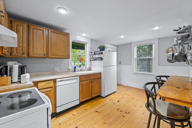 68 Newbury St, Auburn, ME 04210 - kitchen with white appliances, light countertops, wainscoting, light wood finished floors, and brown cabinets