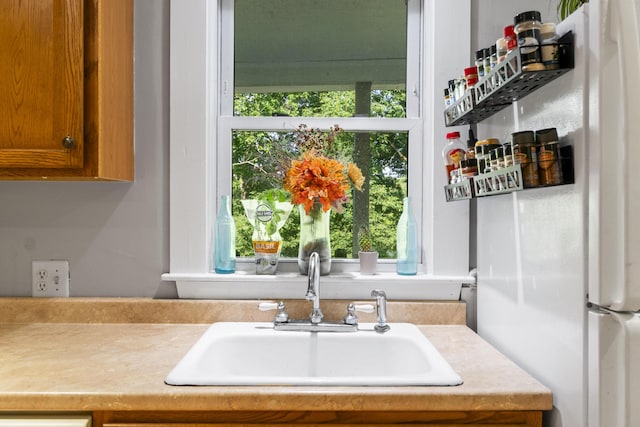 68 Newbury St, Auburn, ME 04210 - kitchen featuring healthy amount of natural light, light countertops, brown cabinets, and freestanding refrigerator