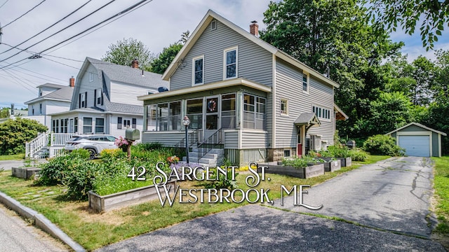 42 Sargent St, Westbrook, ME 04092 - view of front facade featuring an outdoor structure, a chimney, a sunroom, a detached garage, and a vegetable garden