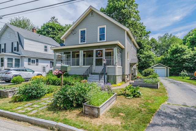 42 Sargent St, Westbrook, ME 04092 - view of front of home with a vegetable garden, a detached garage, an outdoor structure, asphalt driveway, and a sunroom