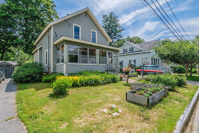 42 Sargent St, Westbrook, ME 04092 - view of front of property with a vegetable garden, a front yard, a storage unit, and a sunroom