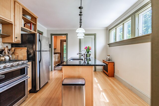 42 Sargent St, Westbrook, ME 04092 - kitchen featuring stainless steel appliances, light wood-style floors, a center island with sink, ornamental molding, and dark stone countertops