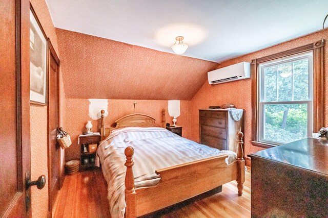 42 Sargent St, Westbrook, ME 04092 - bedroom featuring a wall unit AC, light wood finished floors, wallpapered walls, and vaulted ceiling