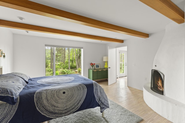 133 Scraggle Point Rd, Saint George, ME 04859 - bedroom with beamed ceiling, multiple windows, a large fireplace, and light wood finished floors