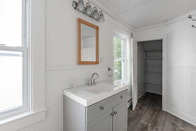 19 Fall St, Biddeford, ME 04005 - bathroom featuring vanity, wood finished floors, a baseboard heating unit, a wainscoted wall, and wood walls