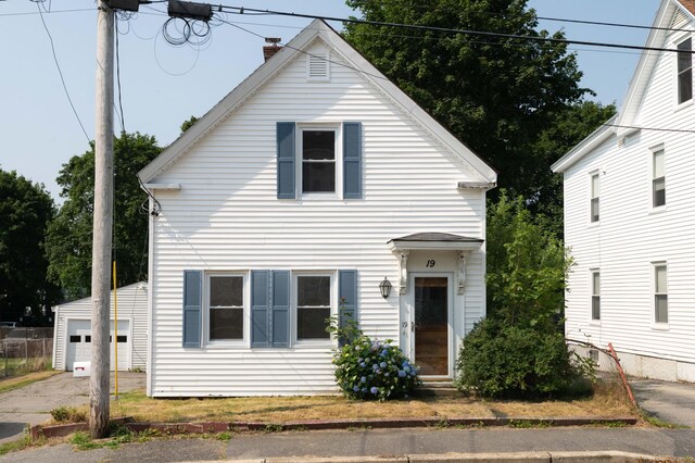 19 Fall St, Biddeford, ME 04005 - view of front of house featuring a garage, a chimney, an outbuilding, and concrete driveway