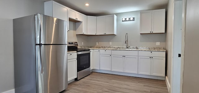 158 Water St, Waterville, ME 04901 - kitchen featuring stainless steel appliances, recessed lighting, white cabinets, light wood-type flooring, and light stone countertops