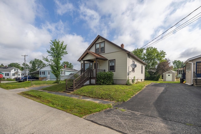 2 Tucker St, Lewiston, ME 04240 - bungalow-style house featuring a storage shed, a chimney, asphalt driveway, a residential view, and a front lawn