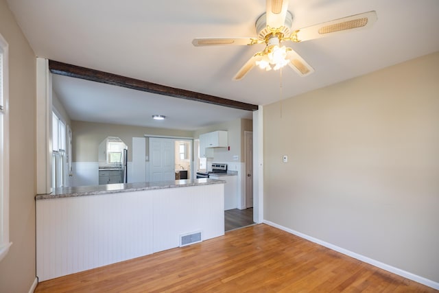 2 Tucker St, Lewiston, ME 04240 - kitchen with stainless steel electric stove, wood finished floors, white cabinets, a ceiling fan, and beam ceiling