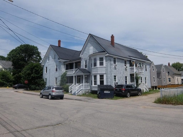 175 Alfred St, Biddeford, ME 04005 - view of front of house with a chimney, a metal roof, and a balcony