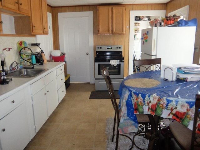 175 Alfred St, Biddeford, ME 04005 - kitchen with stainless steel range with electric stovetop, light countertops, freestanding refrigerator, wood walls, and white cabinetry
