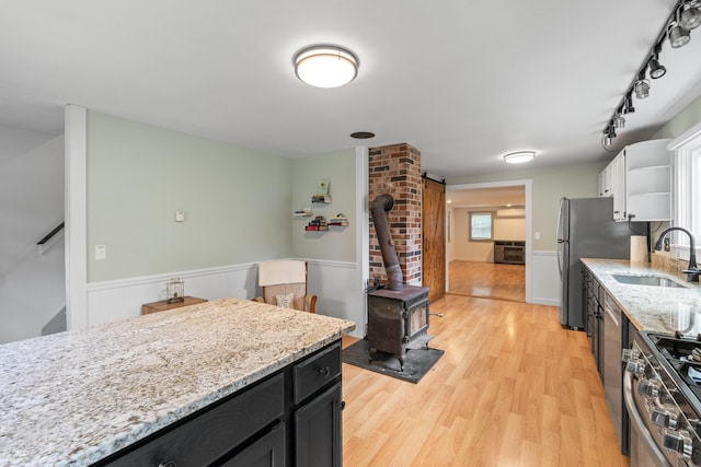 23 Cottage Dr, Friendship, ME 04547 - kitchen with wainscoting, a wood stove, appliances with stainless steel finishes, light wood finished floors, and light stone counters