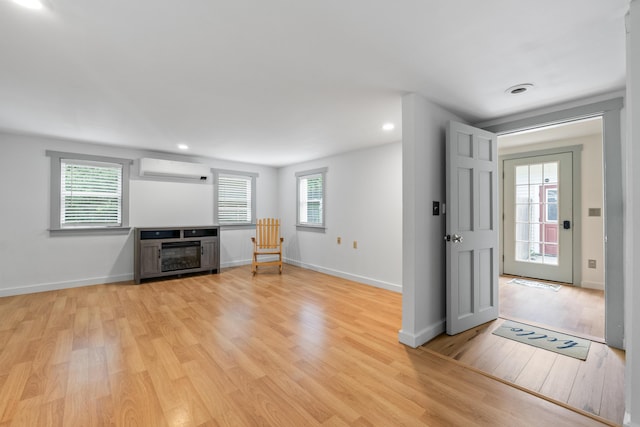 23 Cottage Dr, Friendship, ME 04547 - unfurnished living room with an AC wall unit, light wood-style flooring, and recessed lighting
