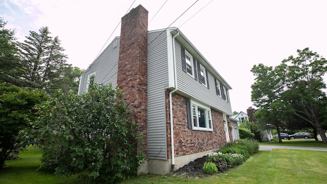 48 Clover Ln, Brewer, ME 04412 - view of side of property featuring brick siding, a chimney, and a lawn