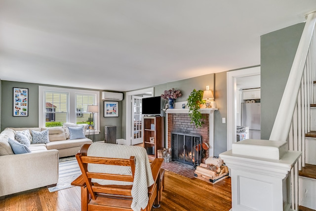 46 Haven Rd, South Portland, ME 04106 - living room with a wall mounted AC, radiator heating unit, wood finished floors, a fireplace, and stairs