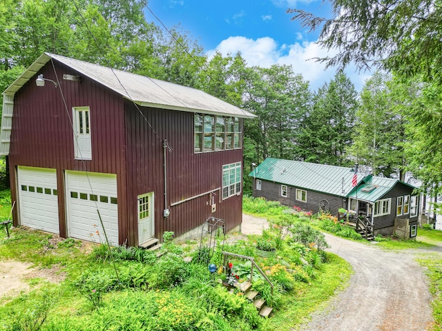 16 Brackett Rd, Dresden, ME 04342 - view of front of house featuring dirt driveway, a garage, and view of wooded area
