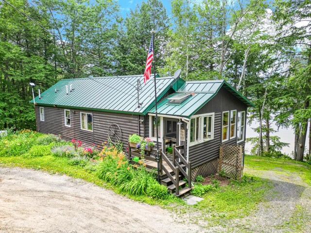 16 Brackett Rd, Dresden, ME 04342 - rustic home featuring a standing seam roof, a metal roof, a deck, faux log siding, and view of wooded area