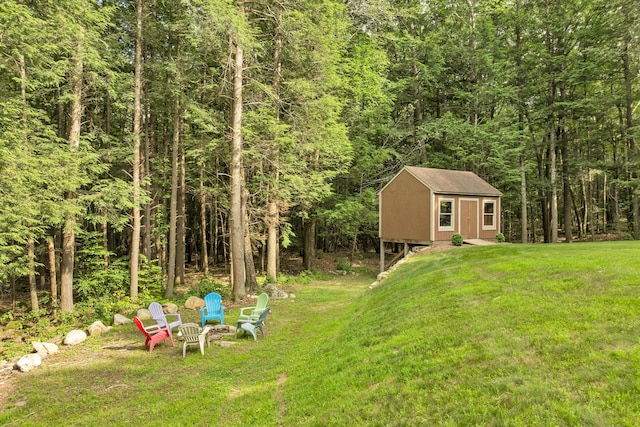 125 Deer Ridge Dr, Barrington, NH 03825 - view of green lawn featuring a wooded view, an outdoor fire pit, and a storage unit
