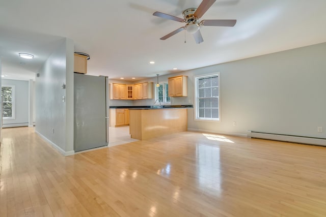 8 Woodside Dr Unit 1, Gorham, ME 04038 - kitchen with freestanding refrigerator, baseboard heating, dark countertops, light brown cabinets, and light wood-type flooring
