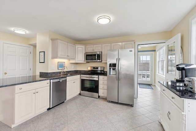 42 Rachel Carson Ln, Wells, ME 04090 - kitchen with stainless steel appliances, a peninsula, dark stone counters, and light tile patterned floors