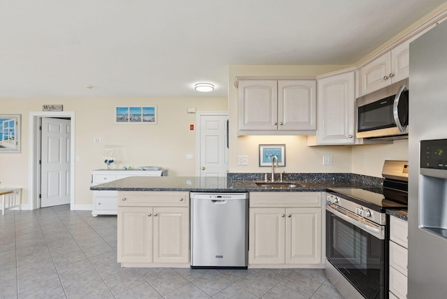 42 Rachel Carson Ln, Wells, ME 04090 - kitchen with stainless steel appliances, light tile patterned floors, a peninsula, dark stone countertops, and cream cabinetry